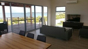 A modern living room with a large TV, a wooden dining table, and a sofa.