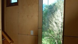 A corner room with a wooden staircase and a large glass door leading to a garden. - The Architects House - Architecturally designed home in a scrubland setting with native birdlife and a bush track to the beach (Marion Bay)