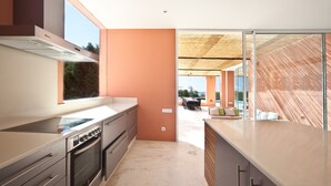 Une cuisine moderne dotée d’une grande fenêtre, d’un four encastré et donnant sur un patio extérieur.