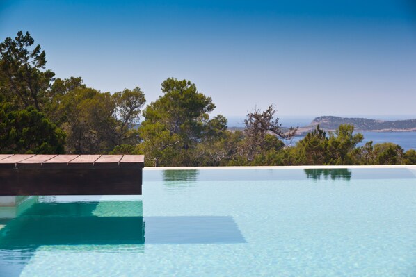 Ein klares Schwimmbecken mit Blick auf das Meer und Bäume.