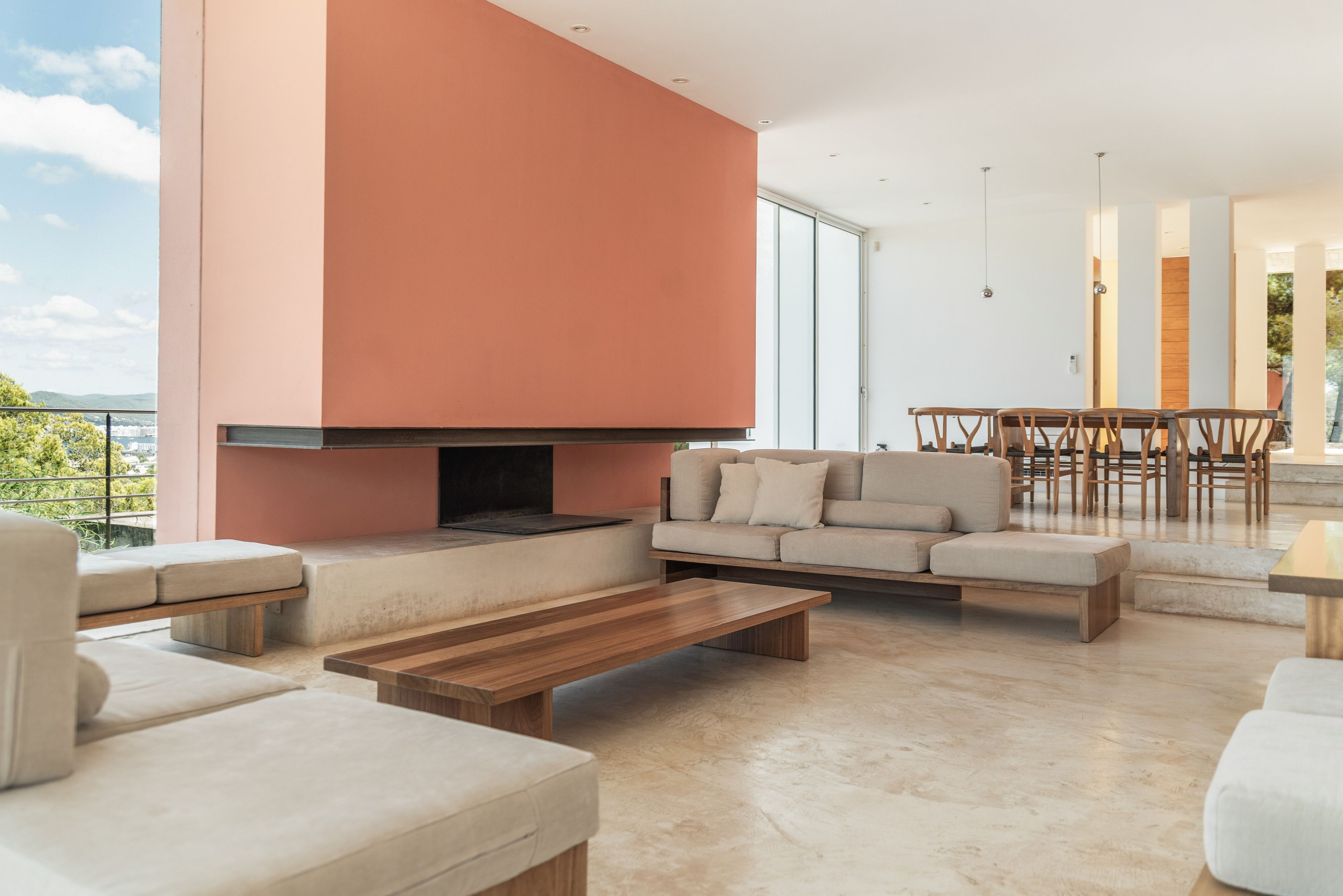 Ein modernes Wohnzimmer mit Kamin, Sofas, einer Essecke und Blick ins Freie.
