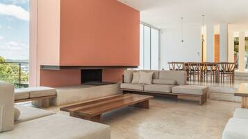 Ein modernes Wohnzimmer mit Kamin, Sofas, einer Essecke und Blick ins Freie.