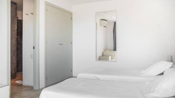 Un dormitorio minimalista con una cama doble, un espejo grande y una puerta que da a un baño.