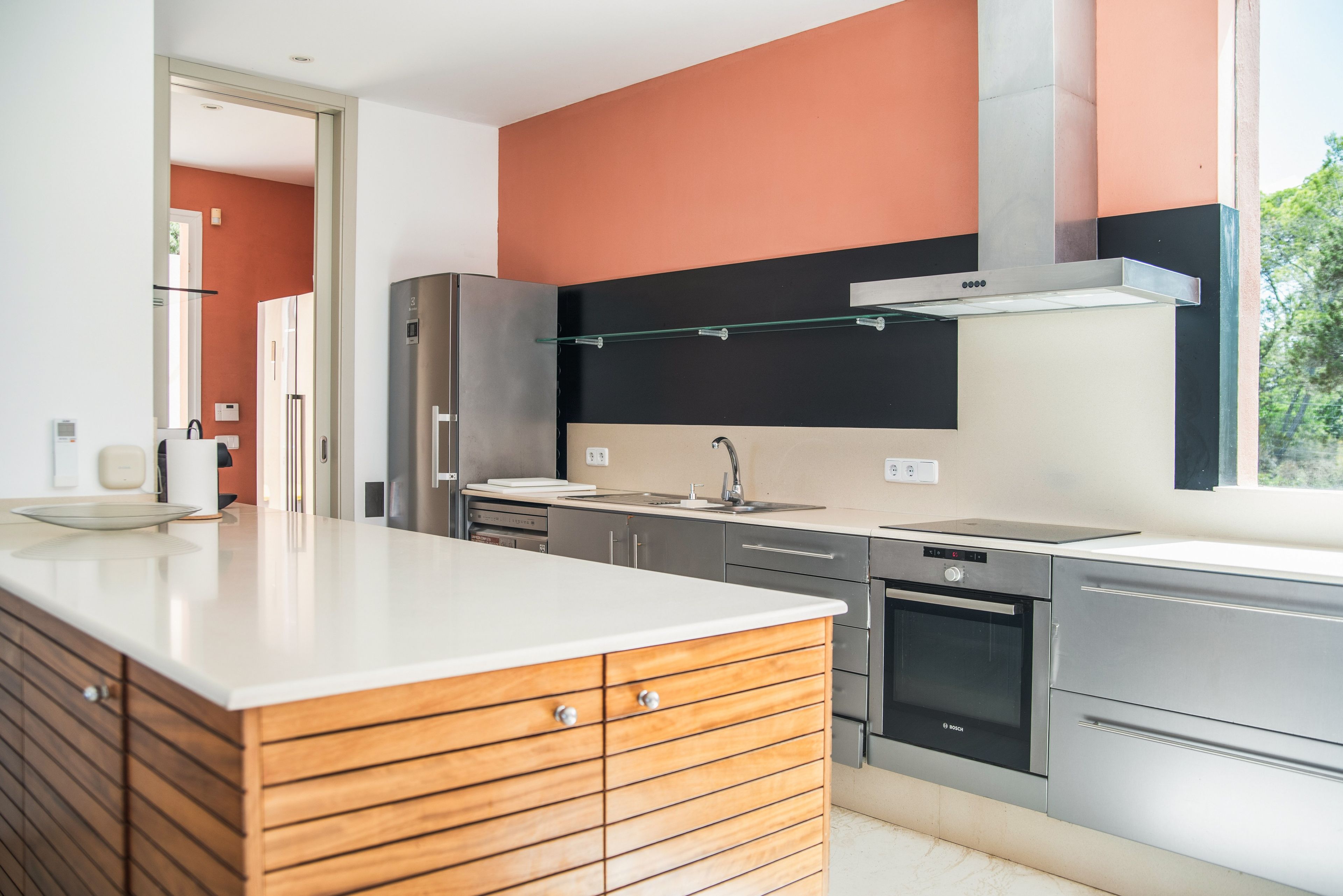 Une cuisine moderne dotée d’appareils électroménagers en acier inoxydable, d’un meuble en bois et d’une grande fenêtre.