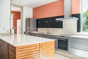 A modern kitchen with stainless steel appliances, a wooden cabinet, and a large window.