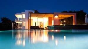 Une maison moderne dotée d’une piscine, de grandes fenêtres et d’un espace extérieur couvert.