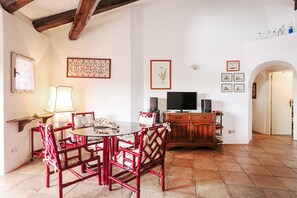 A dining area with a round table, red chairs, a lamp, and a TV on a wooden cabinet.