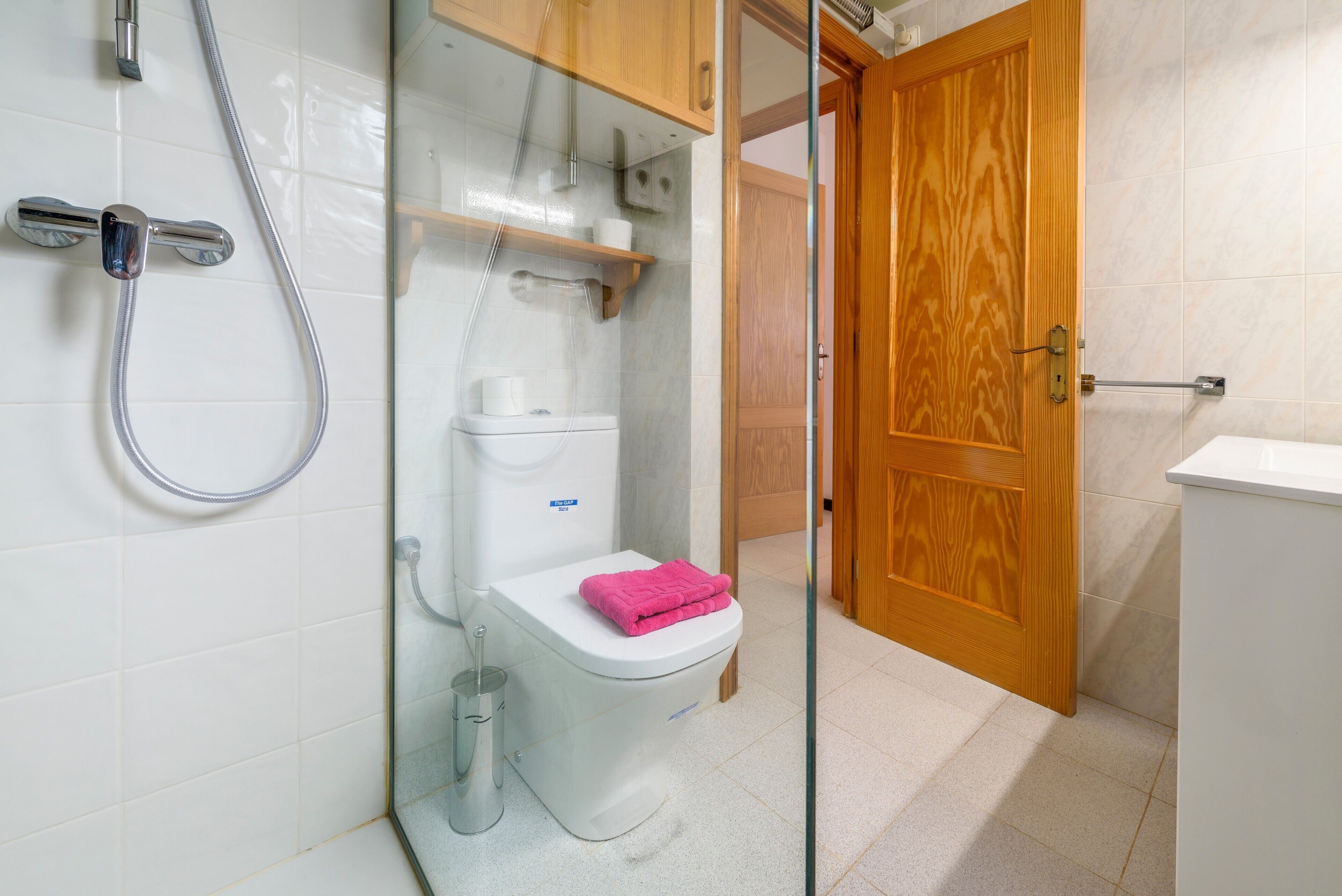 Un baño con ducha, inodoro y puerta de madera.