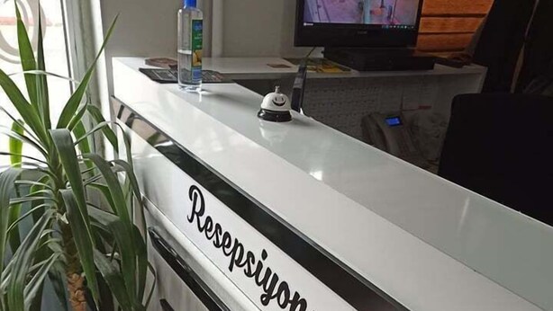 Una recepción con el nombre "Resepsiyon" y una planta en maceta a su lado.