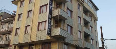 En byggnad med flera våningar, och på fasaden står det med stora bokstäver: ”SUIT HOTEL”.