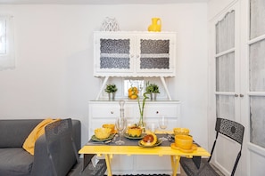 A dining area with a table set for four, a sofa, and a cabinet with decorative items.