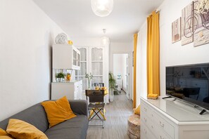 A compact living space with a sofa, a dining table, a TV, and a kitchen area.