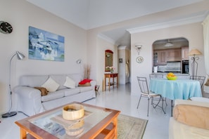 A living room with a sofa, coffee table, and a dining area with a table and chairs. - Elegant Villa "Isa" with Ocean View, Spacious Patios and Garden with Palm Trees (Playa Blanca)