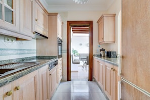 A narrow kitchen with wooden cabinets, a built-in oven, and a countertop with a sink. - Elegant Villa "Isa" with Ocean View, Spacious Patios and Garden with Palm Trees (Playa Blanca)
