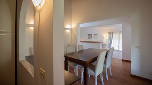 Un comedor con mesa y sillas de madera, una lámpara y vistas a un balcón.
