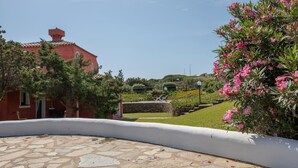 Un edificio rojo con un patio de piedra y una pared blanca.