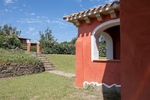 A building with a red exterior, a stone retaining wall, and a pathway leading to a door.