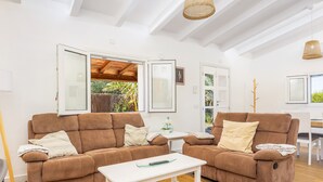Ein Wohnzimmer mit zwei braunen Sofas, einem weißen Couchtisch und einer Glastür, die zu einem Außenbereich führt.