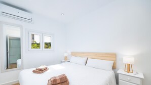 Ein Hotelzimmer mit einem Bett, zwei Nachttischen, einem Spiegel und einer Klimaanlage.