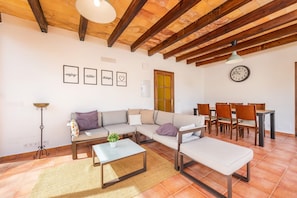 Een woonkamer met een bank, salontafel en een eethoek met stoelen en een tafel.