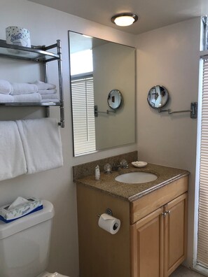 A bathroom with a sink, mirror, towel rack, toilet, and a shelf with towels. - Experience resort living in this privately-owned Ocean Front View apartment at The Imperial Resort, in core of Waikiki on Beach Walk.  The location is steps to world famous Waikiki Beach, world-class shopping and dining. (Honolulu)