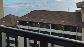 Uitzicht op de oceaan vanaf een balkon met een betegeld dak en een hekwerk.