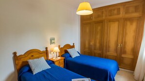 Ein Zimmer mit zwei Betten, einem Holzschrank und einer Pendelleuchte.