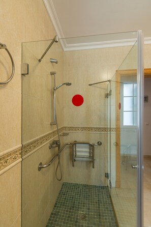 Une douche fermée par des parois en verre, dotée d’une barre d’appui, d’un porte-serviettes et d’un sol carrelé.