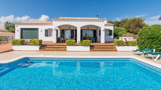 Ein weißes Gebäude mit Pool, Garage und überdachter Terrasse.