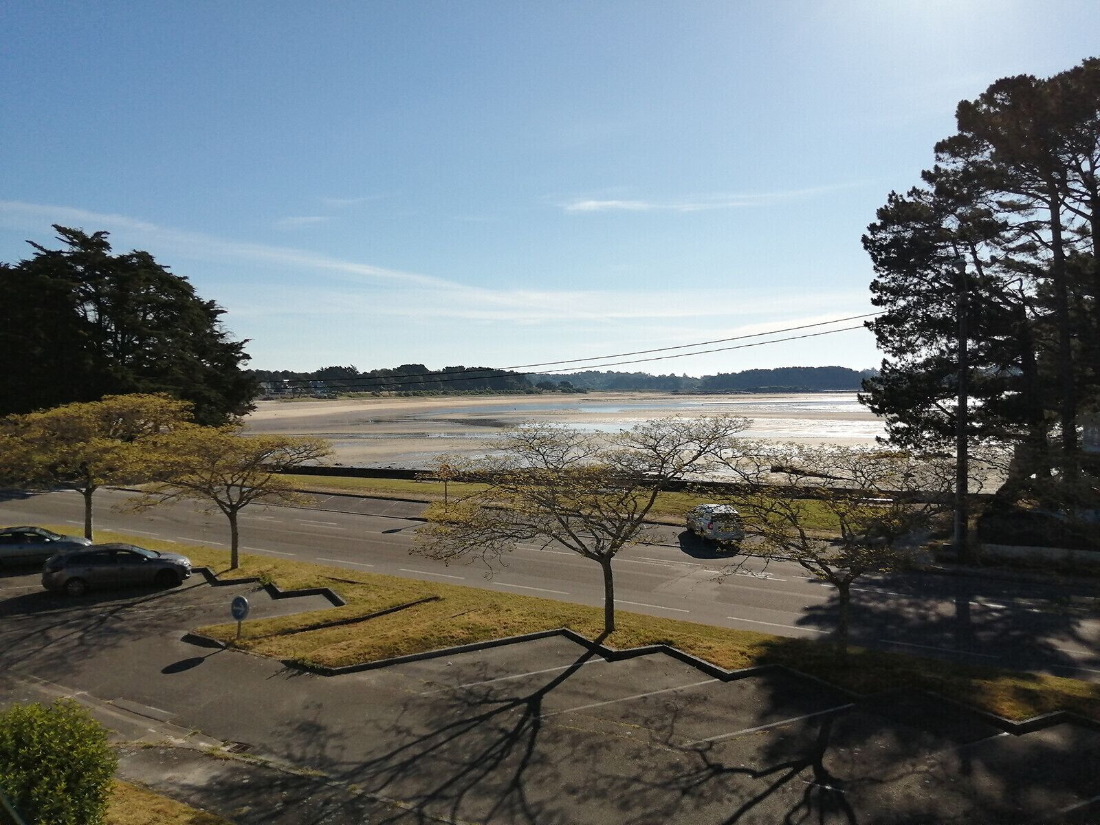 A parking lot with a view of a beach and trees.