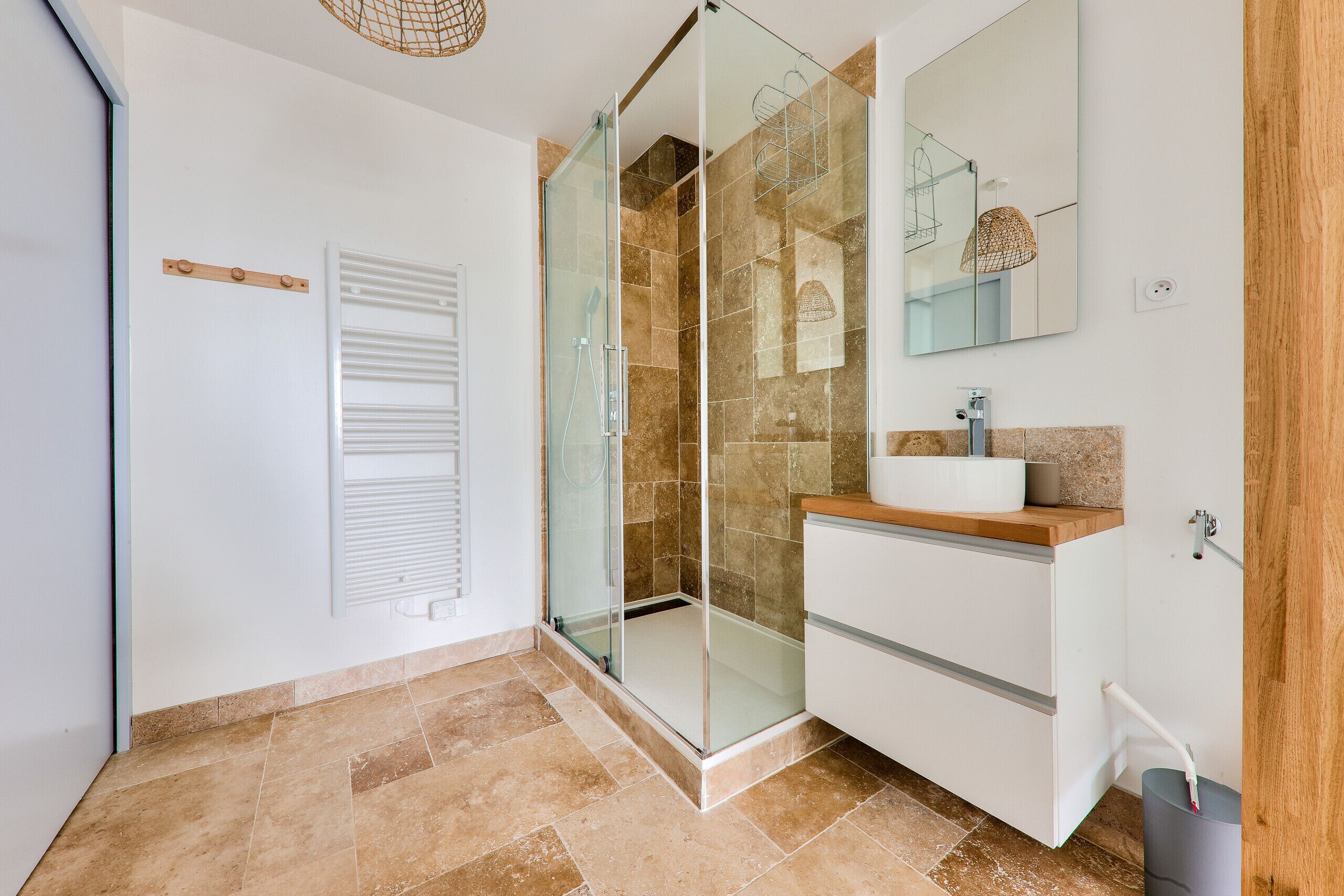Een moderne badkamer met een douchecabine van glas, een witte wastafel en een grote spiegel.