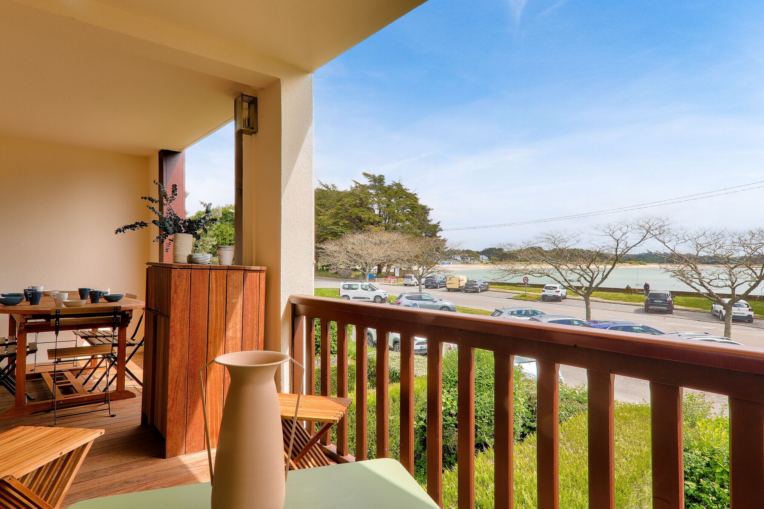A balcony with a wooden table, chairs, and a vase.