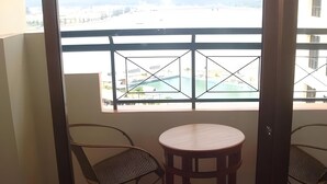 A balcony with a view of a swimming pool and buildings, featuring two chairs and a small round table. - Marina Cove Resort (Lumut)