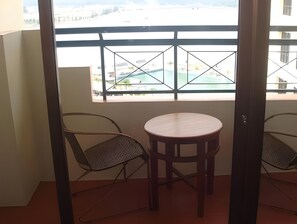 A balcony with a view of a swimming pool and buildings, featuring two chairs and a small round table. - Marina Cove Resort (Lumut)