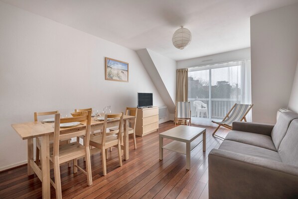 A modern living room with a dining area, a sofa, and a large window.