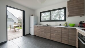 A modern kitchen with a large window, wooden cabinets, and a built-in oven. - New home for 4 adults - 2 children - Garden (Piriac-sur-Mer)