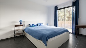 A bedroom with a bed, a nightstand, a lamp, and a window with curtains. - New home for 4 adults - 2 children - Garden (Piriac-sur-Mer)