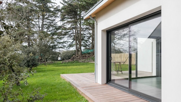 A modern house with a wooden deck and a sliding glass door leading to a patio. - New home for 4 adults - 2 children - Garden (Piriac-sur-Mer)