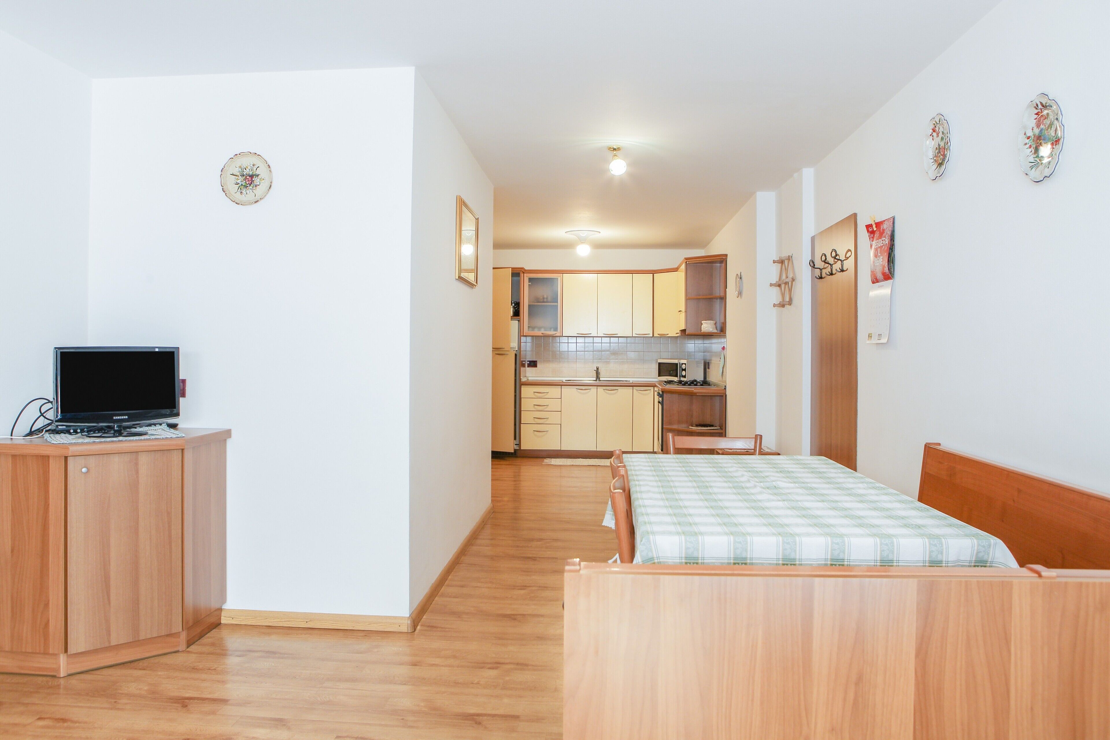 A bedroom with a bed, a desk with a computer, a kitchenette, and a bathroom.