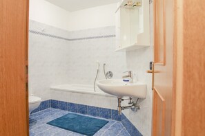 Une salle de bain avec un lavabo blanc, une baignoire et des toilettes.