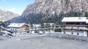 Un refugio de montaña con terraza de madera y vistas a montañas nevadas.