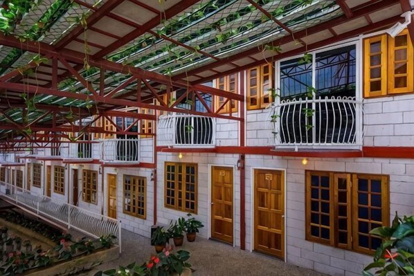 Un bâtiment abrité, doté de plusieurs balcons, de portes en bois et de plantes en pot.