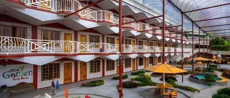 A hotel with multiple balconies, a central courtyard with seating, and a greenhouse structure.