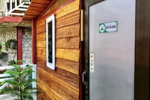 Pared exterior de madera con una ventana y una puerta que dice 'SURAU'.