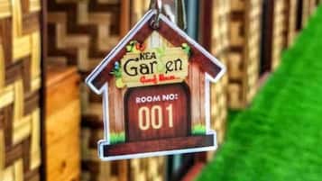 A wooden house-shaped keychain with 'KEA Garden' and 'Room No: 001' written on it.