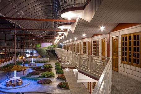 A spacious atrium with a central staircase, seating areas, and a variety of plants.. Kea Garden Mini Chalet