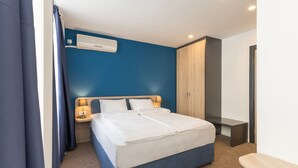 Een moderne hotelkamer met een groot bed, een nachtkastje met een lamp, een kledingkast en een airconditioner aan de muur.