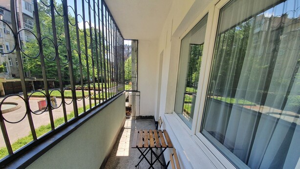 Een balkon met een houten bankje en een metalen hekwerk.