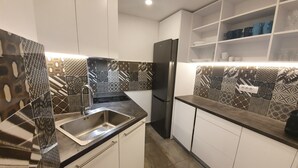 Een moderne keuken met witte kastjes, een roestvrijstalen spoelbak en betegelde spatwand.