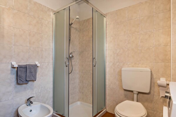 Une salle de bain avec une douche à parois de verre, un lavabo et des toilettes.